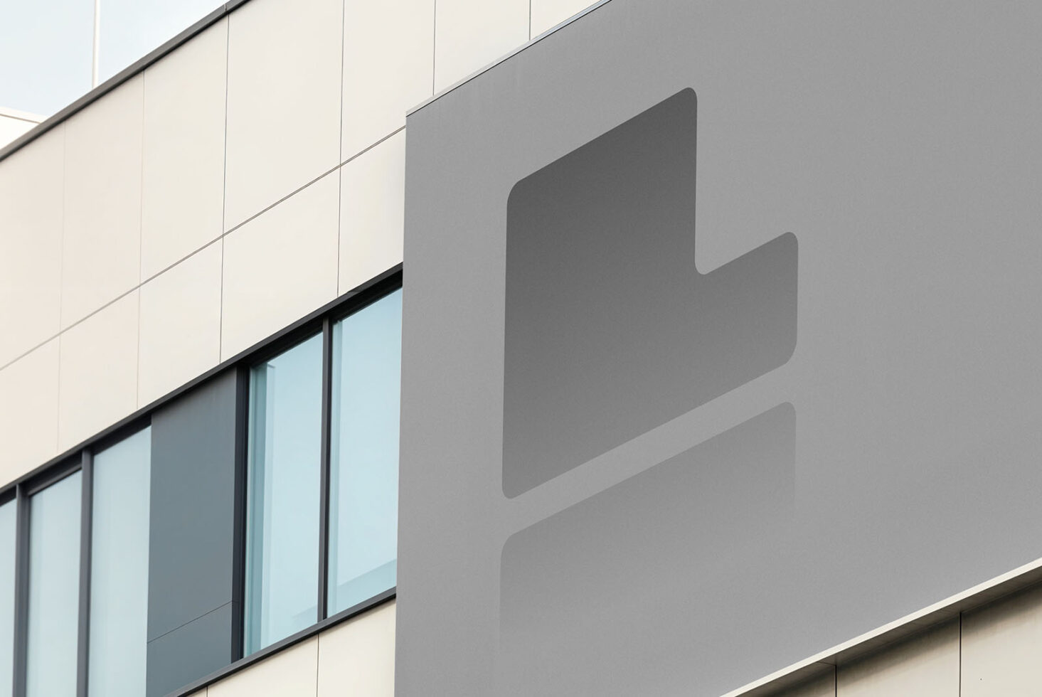 Modern building facade with blank gray sign on concrete wall beside glass windows