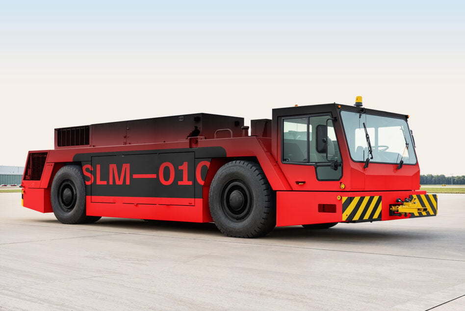 Red industrial tug boat with yellow striping on flat airport surface