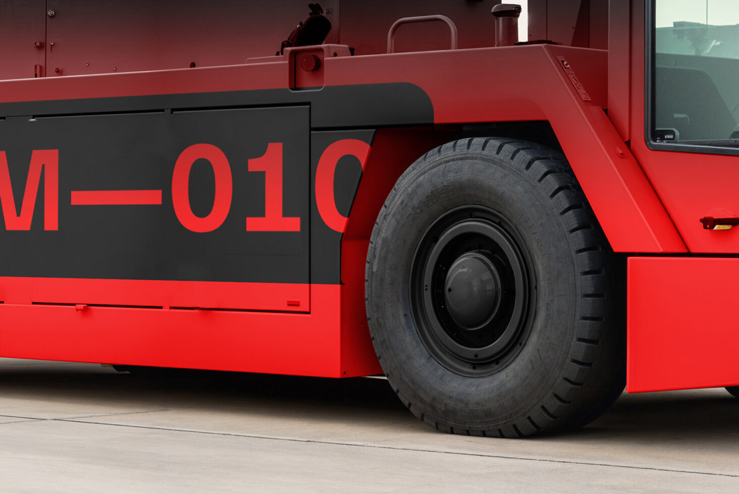 Close-up of a red industrial vehicle with large black tire and bold red lettering on black background. Perfect for mockup or graphic design projects.