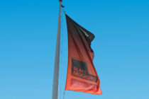 Red flag with black top section waving on flagpole in bright daylight
