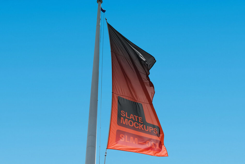 Red flag with black top section waving on flagpole in bright daylight