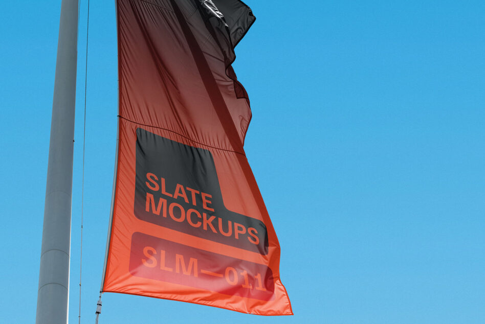 Red flag with black stripe billowing on pole against clear blue sky