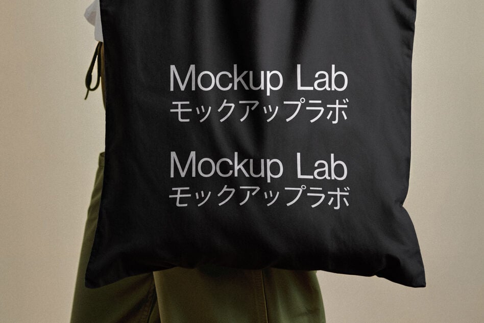 Black tote bag with white text showing Mockup Lab branding in English plus Japanese