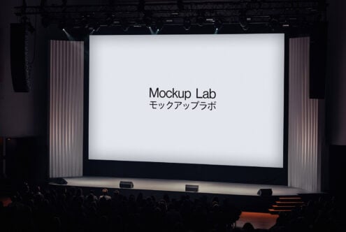 Stage presentation with a large screen displaying text Mockup Lab. Ideal for design resources mockups or templates. Audience seated in a theater setting.