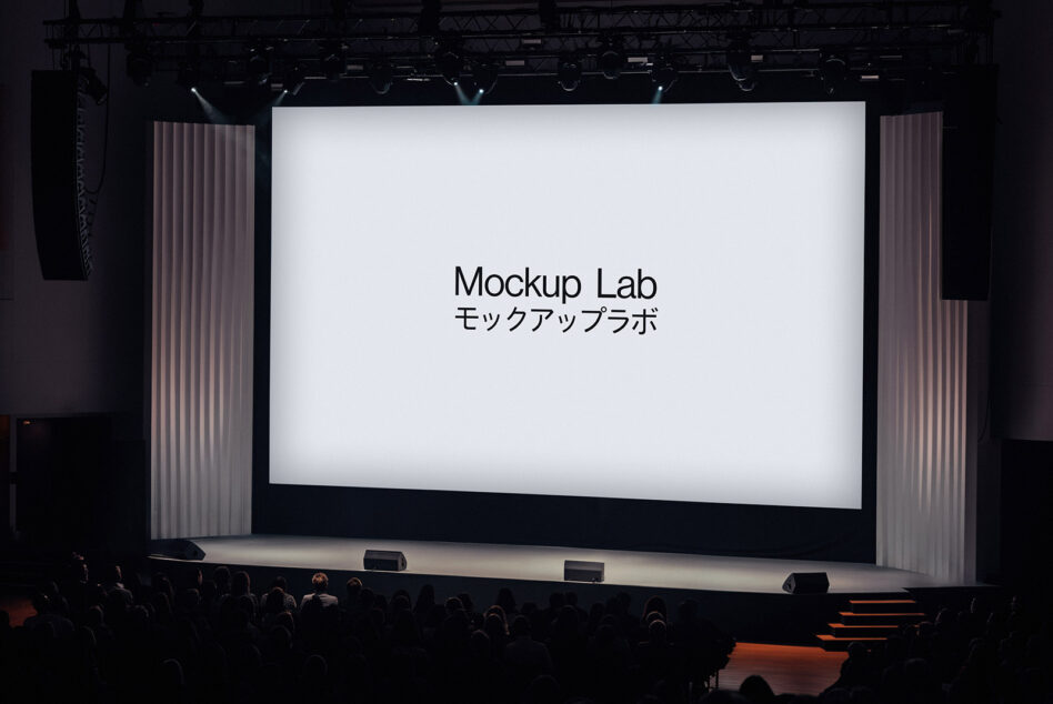 Stage presentation with a large screen displaying text Mockup Lab. Ideal for design resources mockups or templates. Audience seated in a theater setting.
