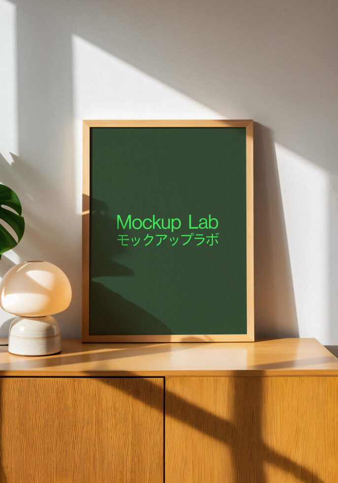 Framed mockup on wooden cabinet with modern decor and leafy plant. Ideal for showcasing designs for interior accents and graphic presentations.