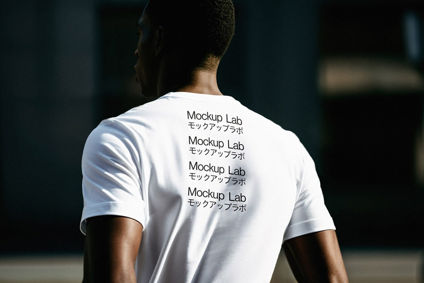 Back view of a person wearing a white t-shirt mockup displaying Mockup Lab text. Perfect for designers to showcase apparel graphics and templates.