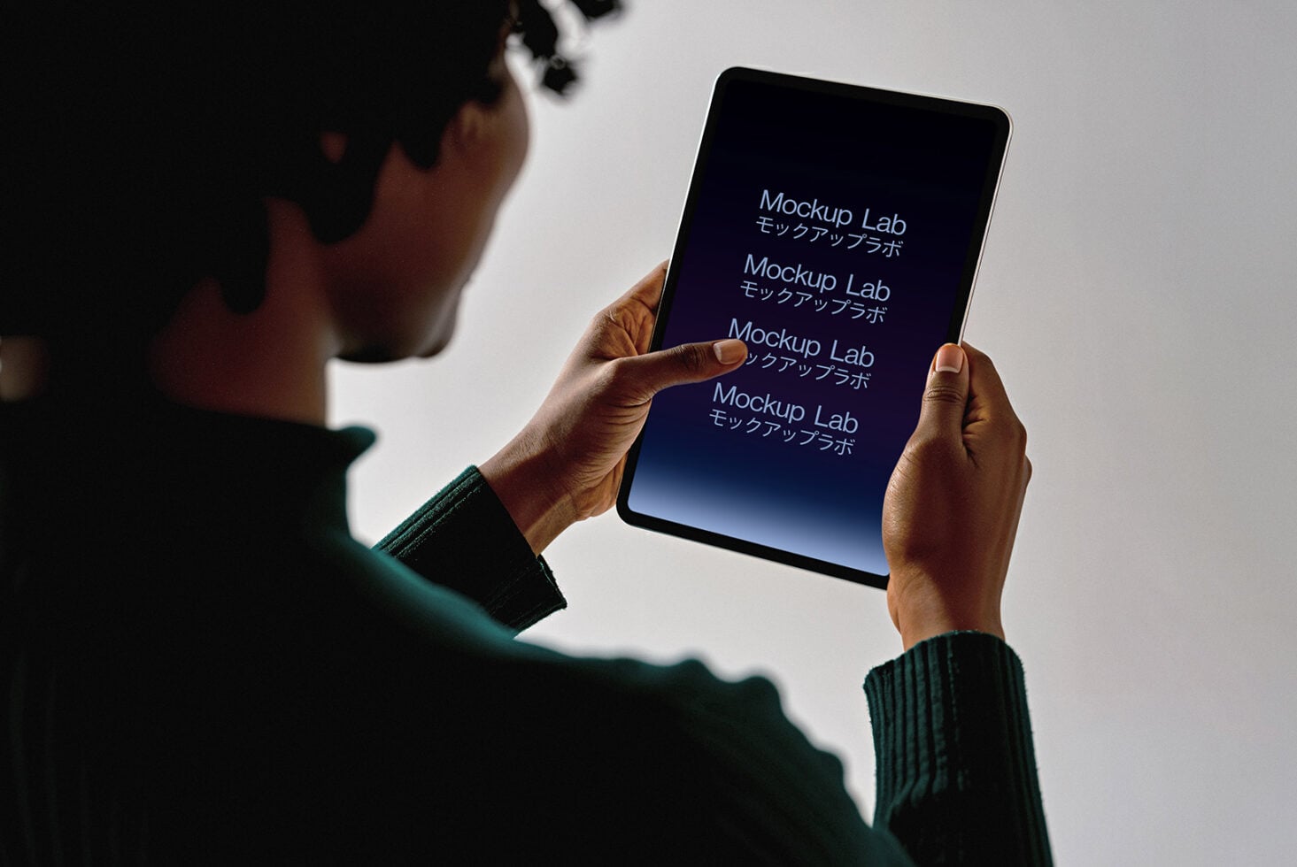 Hands holding tablet with dark screen showing repeating text lines