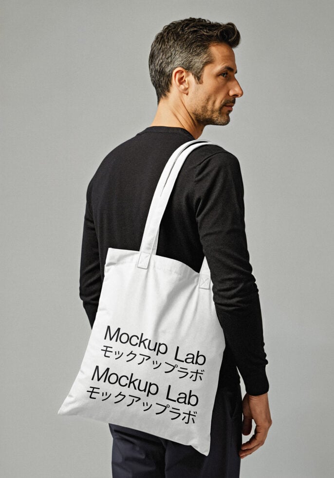 Tote bag mockup featuring a man in casual attire holding a white cotton tote with printed text. Ideal for branding design projects and presentations.