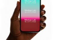 Hand holding phone with teal-to-pink gradient display on clean white surface