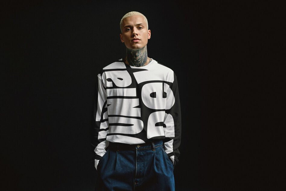 Model wearing a graphic black and white long-sleeve shirt with bold typography. Fashion mockup for graphic design, typography, and apparel design.