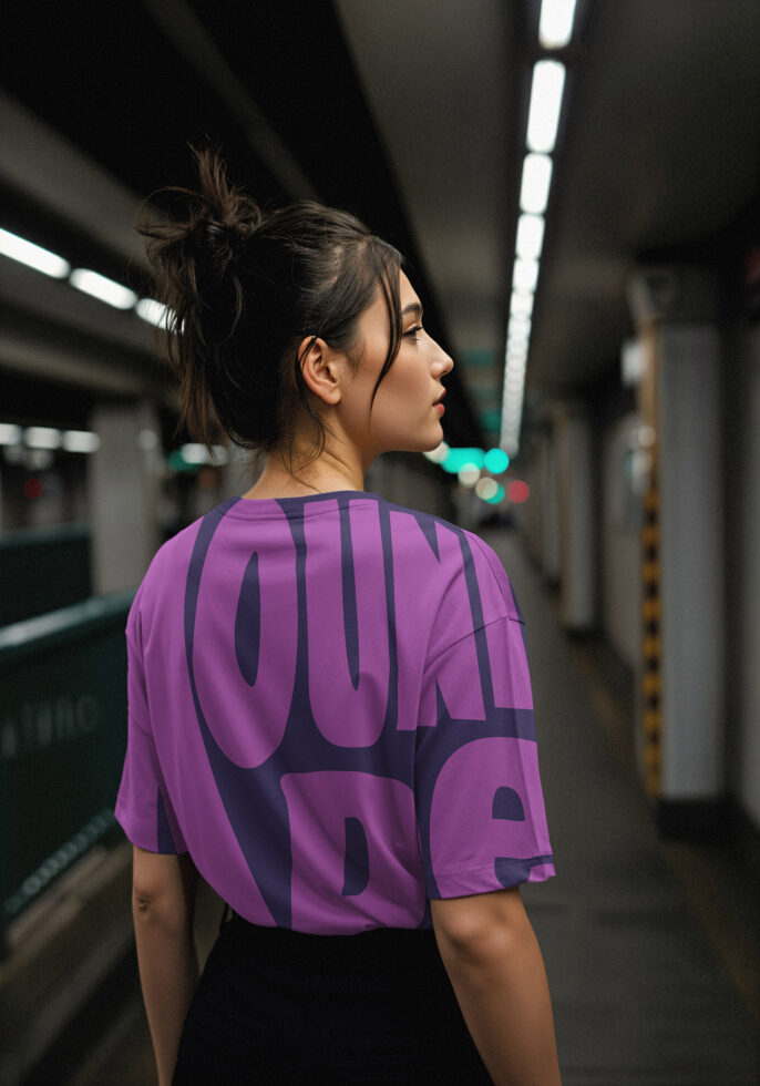 Woman wearing a purple oversized graphic tee in a dimly lit underground setting perfect for showcasing urban fashion mockups and streetwear templates