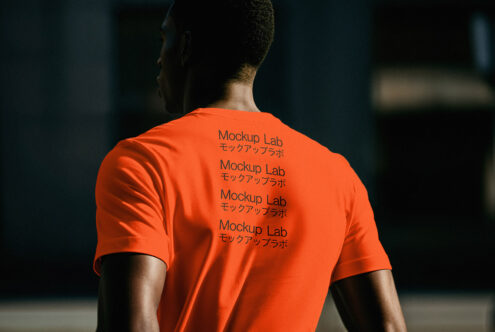 Back view of a person wearing an orange T-shirt with Mockup Lab logo in English and Japanese. Ideal for apparel design mockups and creative graphic projects.