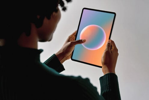 Person holding tablet displaying a colorful abstract sphere design, suitable for mockup use. Perfect for graphic designers and template creation.