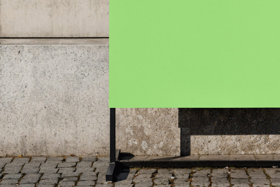 Urban street mockup showcasing a vibrant green blank billboard against a textured concrete wall perfect for design presentations and advertising graphics.