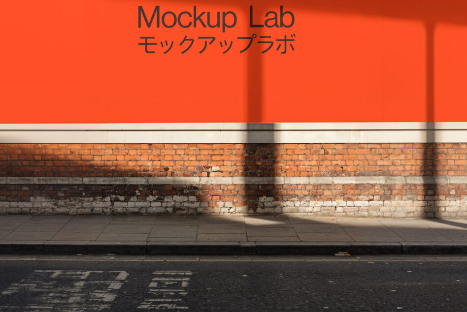 Street scene mockup featuring an orange wall with Japanese and English text. Ideal for showcasing branding designs. Urban brickwork background.