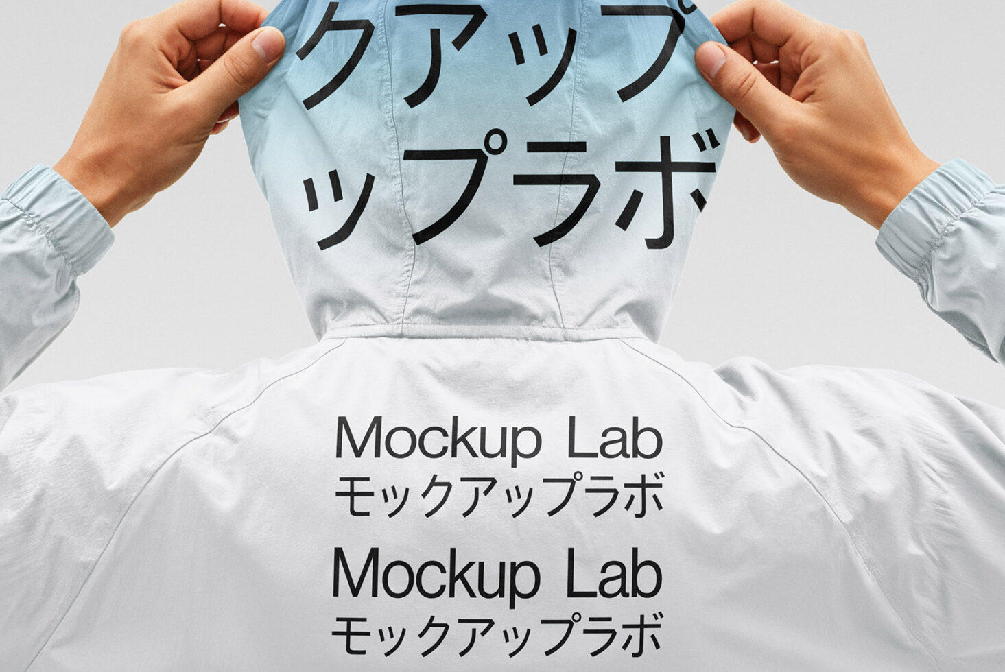 Person adjusting a hoodie printed with Mockup Lab in English and Japanese. Ideal for designers seeking fashion templates and mockup assets.