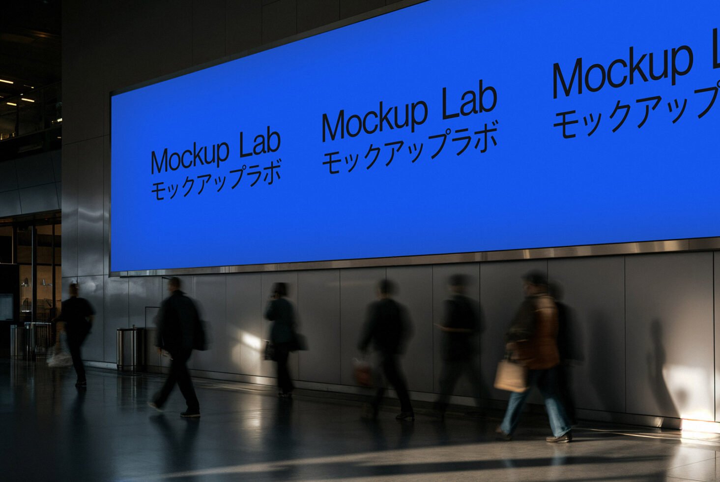 Large indoor wall display showcasing Mockup Lab branding in English and Japanese. Blurred silhouettes of people walking. Keywords: mockup, design, urban.