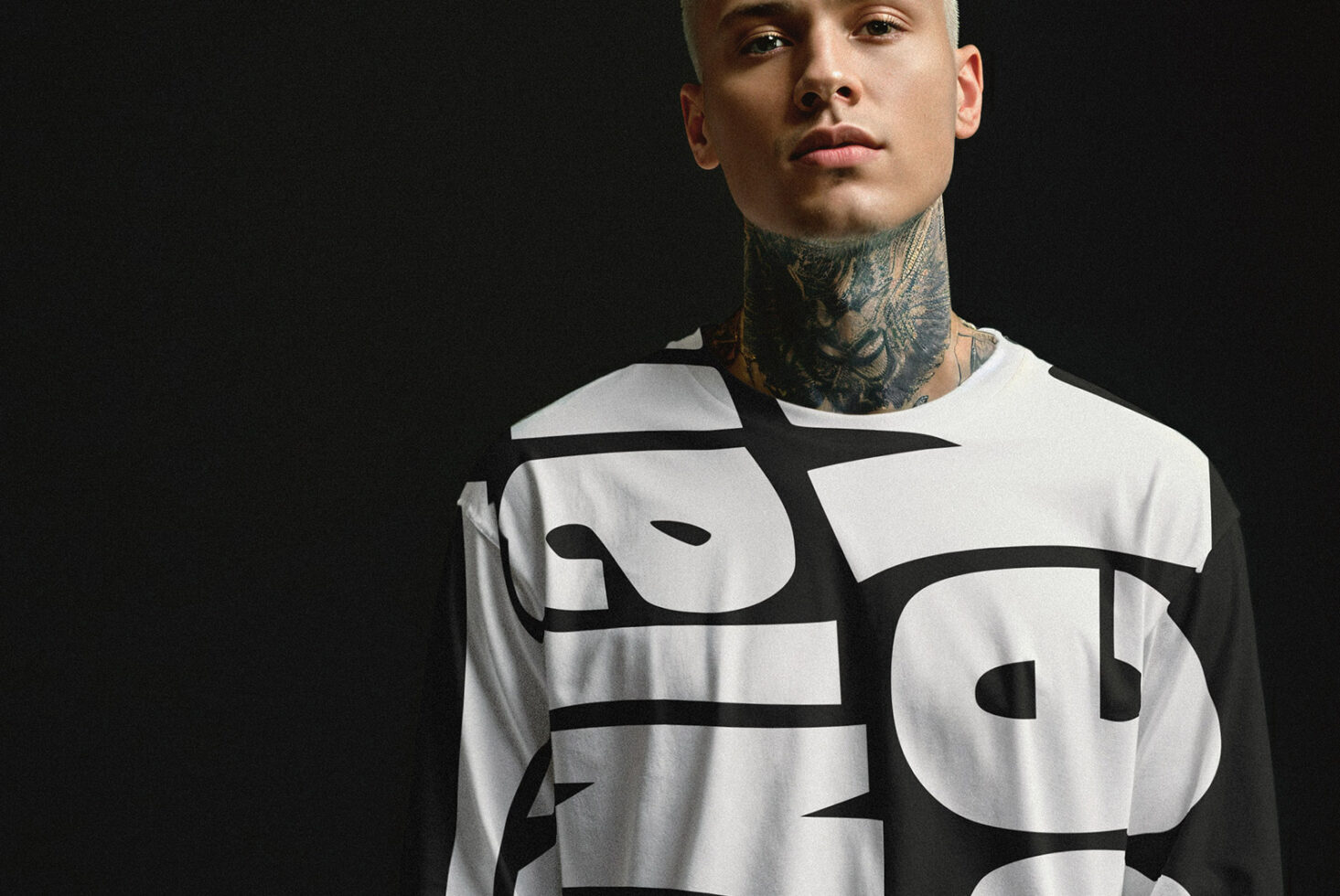 Tattooed man wearing bold typography graphic shirt against dark background. Ideal for design mockups and fashion graphics projects.