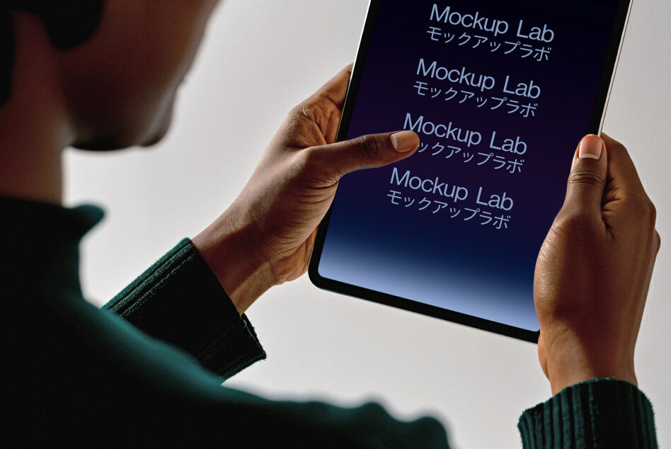 Person holding a tablet displaying Mockup Lab text in English and Japanese. Digital device mockup for designers. SEO keywords: tablet mockup design.