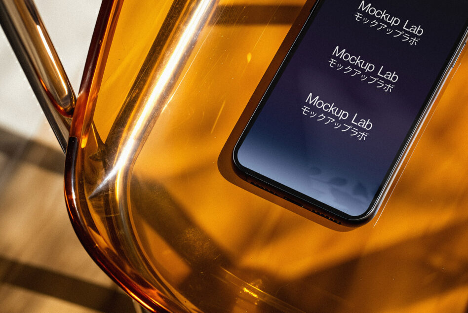 Smartphone screen mockup displaying text in Japanese set on a stylish amber chair. Ideal for designers seeking modern digital assets with an elegant touch.