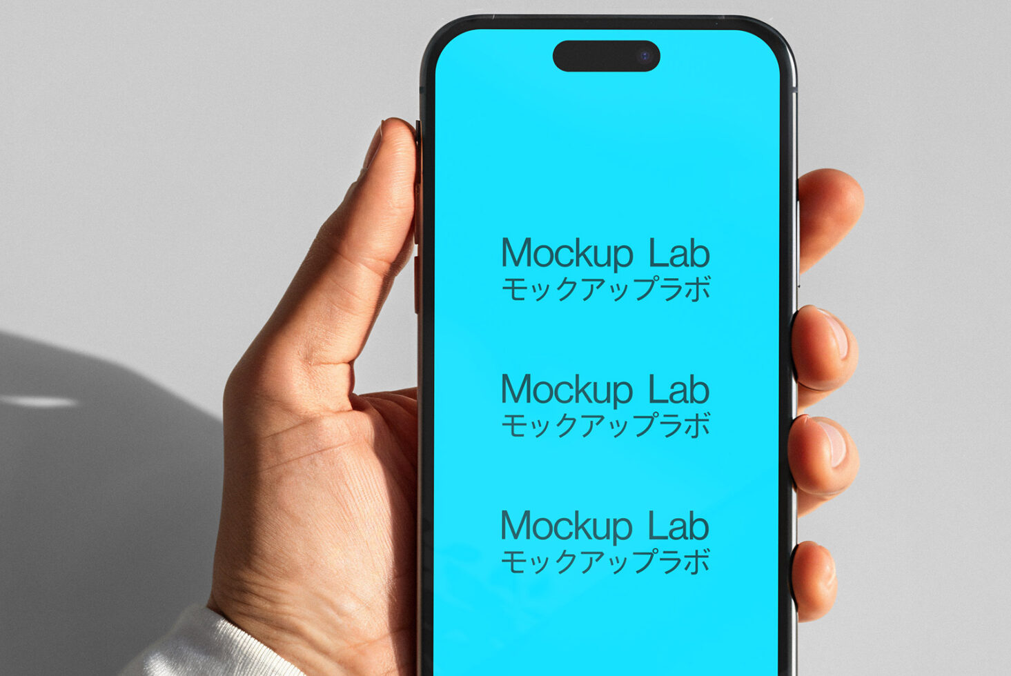 Smartphone in hand held upright showing bright cyan screen with text stacked vertically