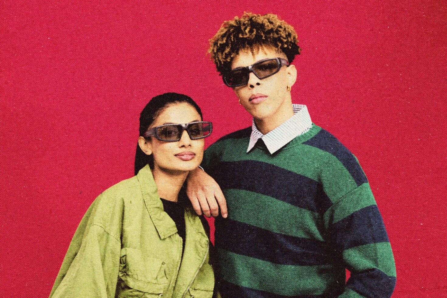 Stylish fashion mockup featuring two models in sunglasses and trendy outfits against a bold red background. Perfect for designers seeking retro aesthetics.