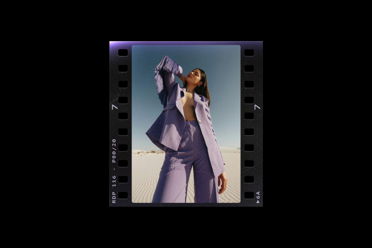 Woman in a stylish purple suit poses confidently in an outdoor setting framed by a vintage film strip design. Perfect for fashion graphics and mockups.