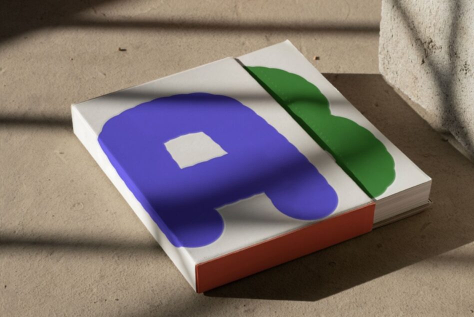 Square book with blue rounded form on white cover, green ribbon