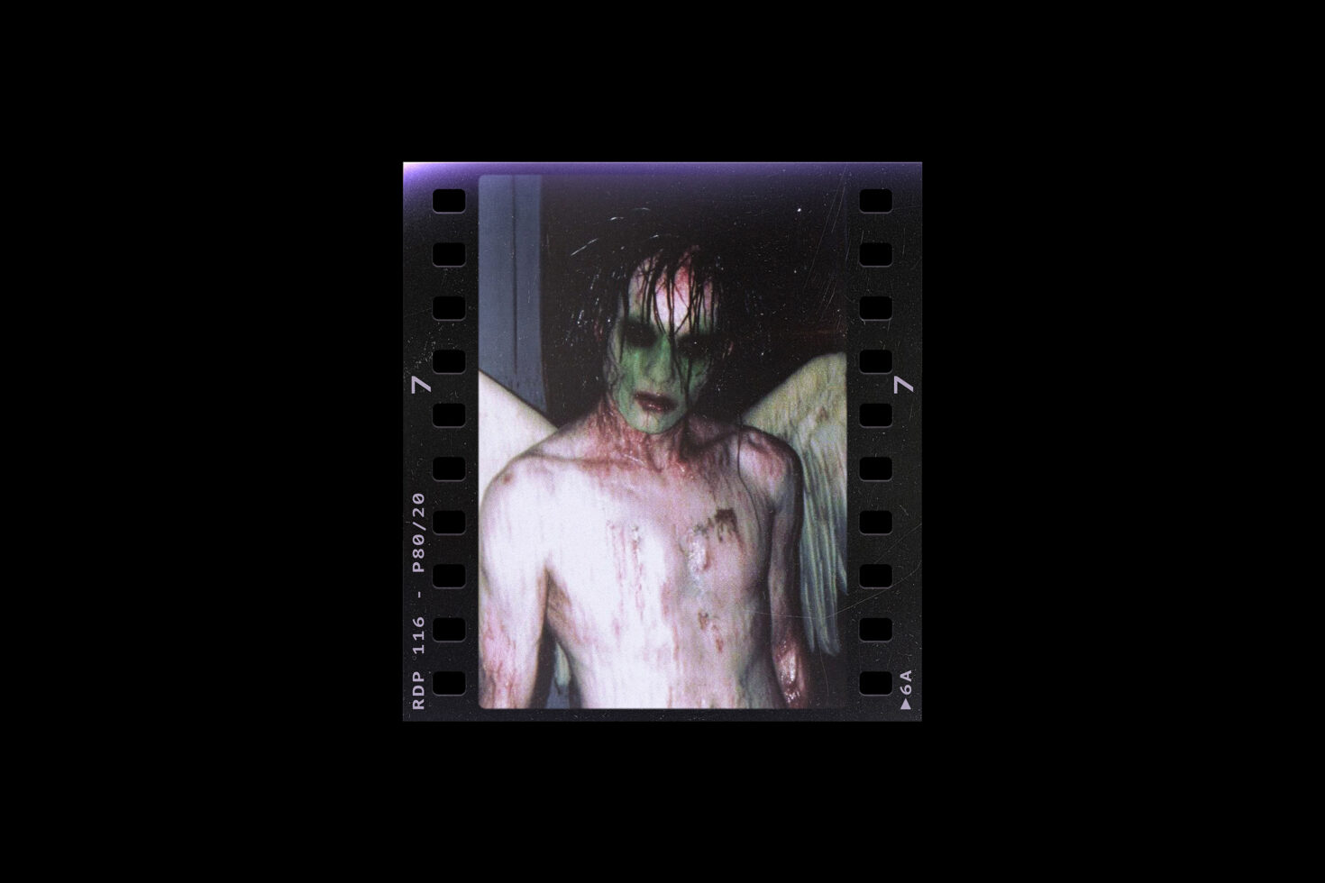 Eerie grunge-inspired graphic of a figure with green face and angel wings in filmstrip format. Perfect for horror-themed design projects and mockups.