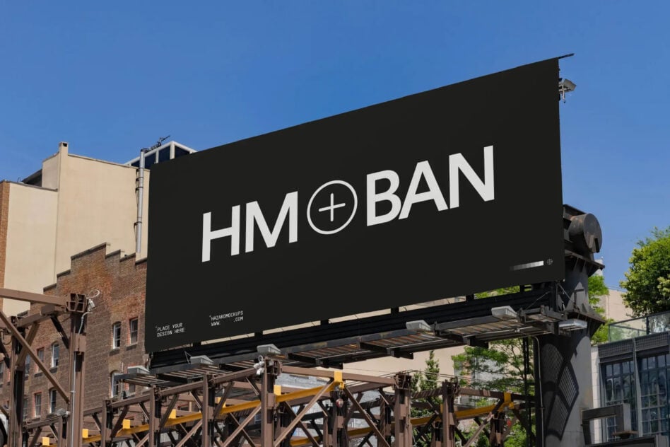 Black billboard mockup with white text on industrial metal frame structure between buildings