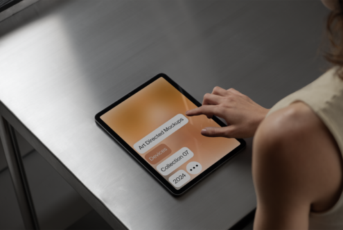 Tablet mockup on metal table with hand interacting on screen displaying art directed mockups collection 2024, perfect for design presentations.