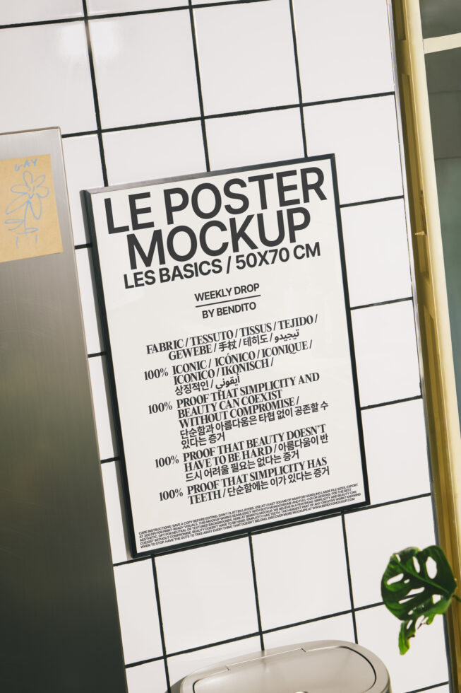 Black poster mockup on grid wall with gold frame, green plant leaf below