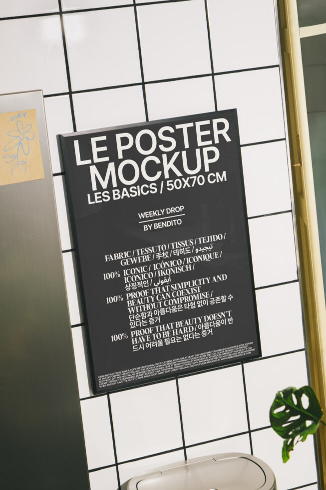 Black poster mockup on grid wall with gold frame, green plant leaf below