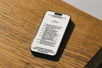White iPhone mockup with black text on wood surface, angled view