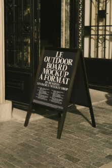 Black A-frame sidewalk sign with white serif typography on street