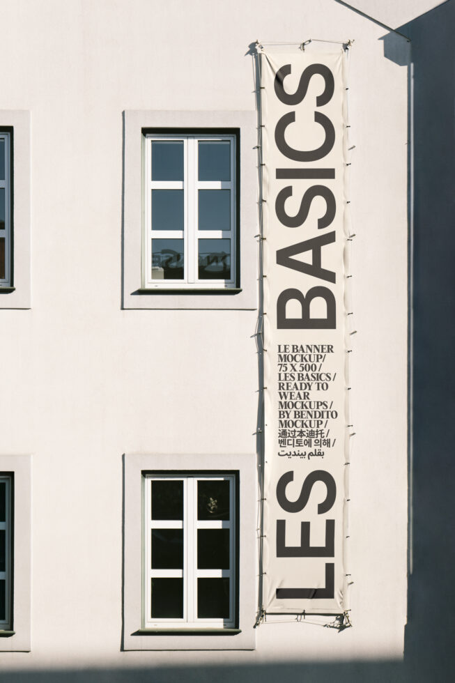 Building facade with large vertical banner reading LES BASICS beside windows. Ideal for urban mockups, design presentations, or showcasing graphics.