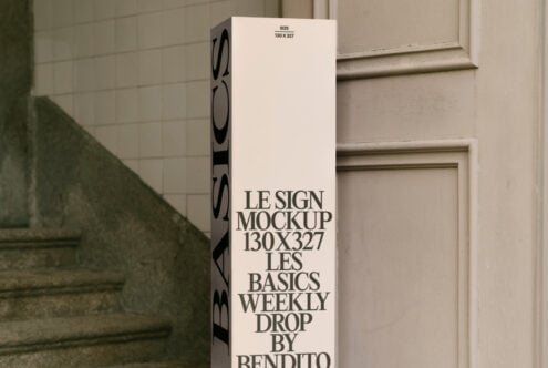 Vertical sign mockup in a minimal setting by stairs and door. Keywords: mockup, sign, design, template, minimalist, vertical, typography, graphic design.