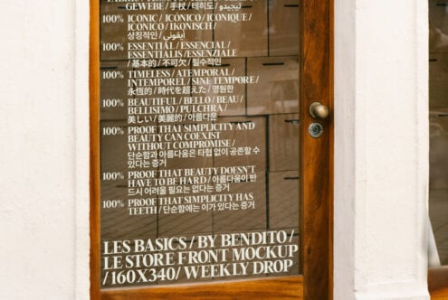 Wooden store front door with multilingual text about simplicity and beauty. Keywords: mockup, design, typography, storefront, wood texture, graphic asset.