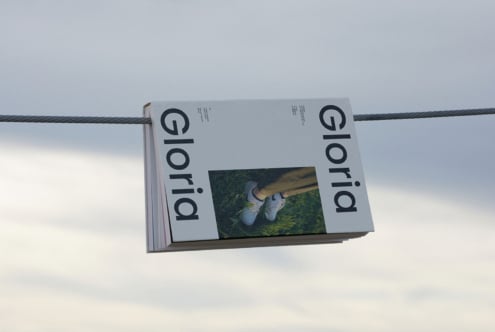 Magazine mockup featuring a minimalist design titled Gloria hanging on a cable. Ideal for showcasing print layout, typography, and branding concepts.