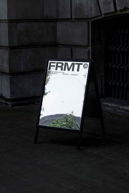 Black A-frame sidewalk sign with white header against concrete building backdrop