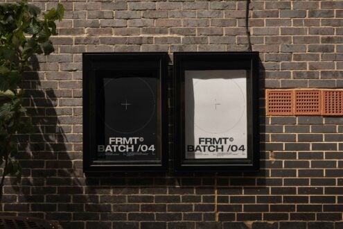 Outdoor brick wall with two framed black and white poster mockups for designers featuring modern typography and grid layout shadows cast over.