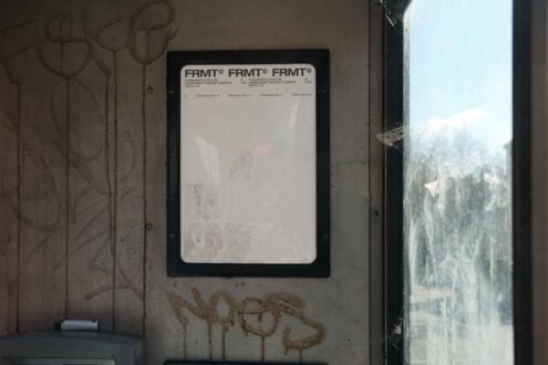 Urban photo showcasing a grungy mockup display inside a bus stop with graffiti on textured walls suitable for graphic design templates and effects.