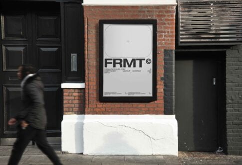 Urban scene showcasing a large framed street poster mockup on a brick wall with a blurred figure walking by; ideal for graphic design presentations.
