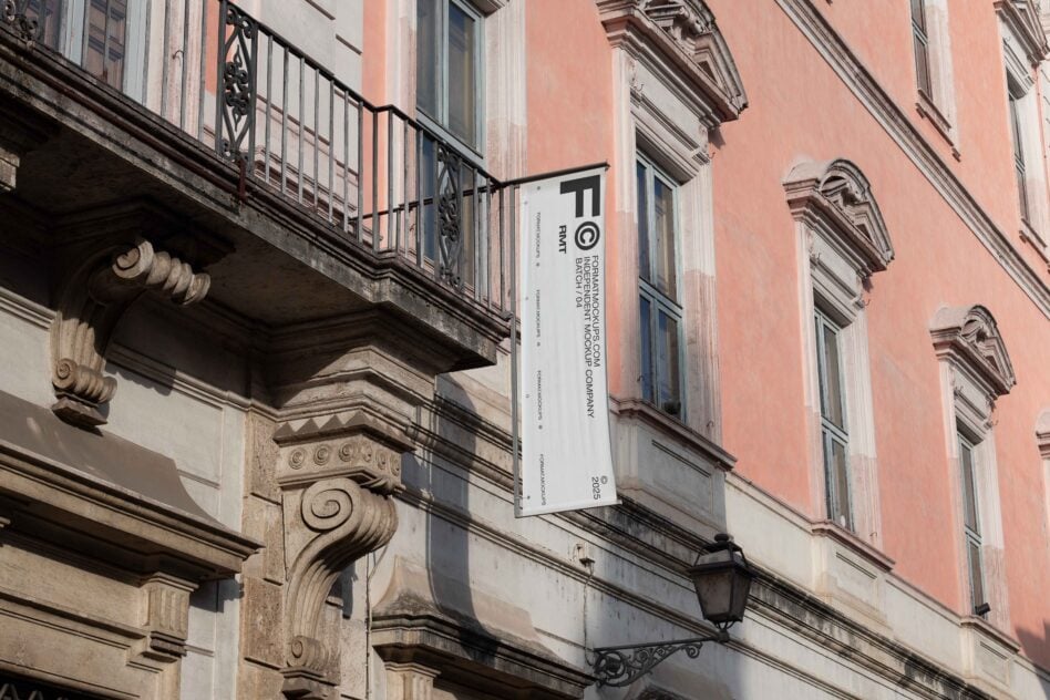 White vertical banner hanging on peachy building with ornate architectural details