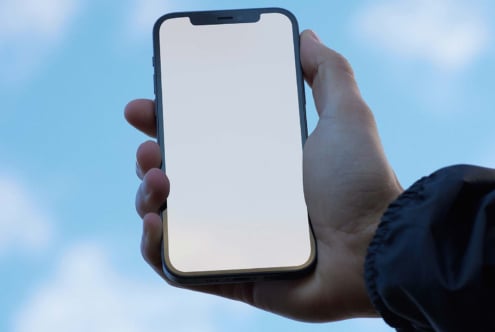 Smartphone in hand mockup with blank screen against blue sky ideal for app design showcase UI UX designers technology digital assets templates modern.