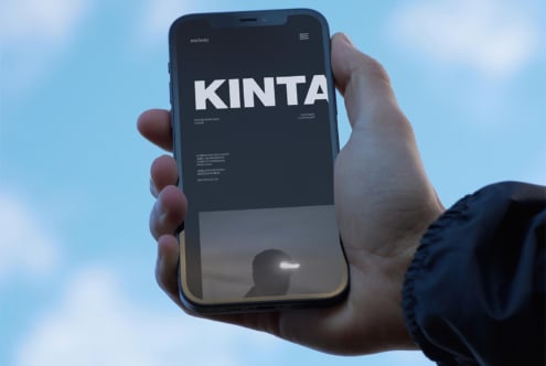 Mockup of a hand holding a smartphone displaying a modern website design with bold typography. Ideal for designers seeking mobile interface templates.