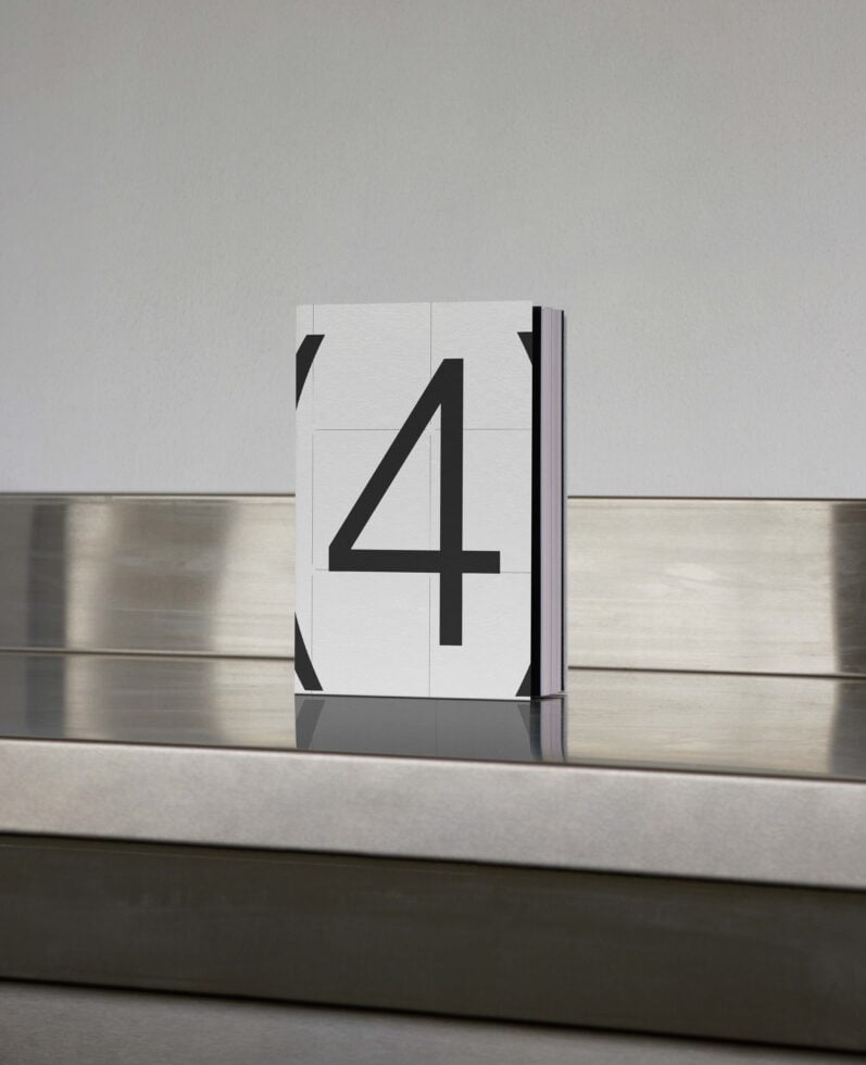 Book mockup with large number 4 on cover placed on reflective metallic surface. Ideal for graphic designers in need of professional presentation templates.