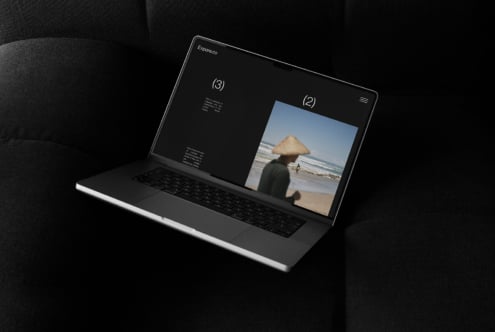 Laptop mockup showing a website design with a travel photo on screen stylishly placed on a dark sofa perfect for showcasing creative design projects.