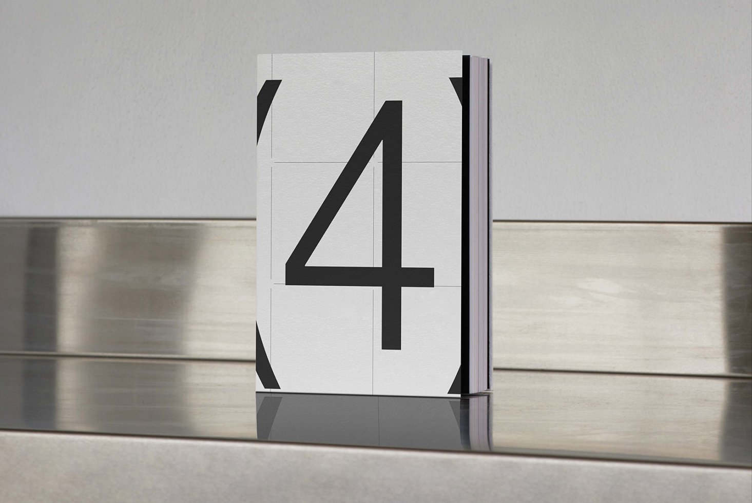 Minimalist book cover mockup featuring large black number 4 on white background placed on reflective metallic surface suitable for designers.